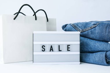 Kağıt alışveriş torbaları, kot giysileri olan kısa pano satışı. İnternetten alışveriş konsepti. Promosyon reklamcılığı. Tatil Siber Pazartesi.