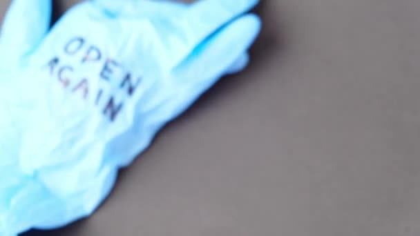 Sprängd blå latex kirurghandske på svart bakgrund. Öppnar kassaskåpet. Öppna igen text skriven på medicinsk handske. Nytt normalt — Stockvideo