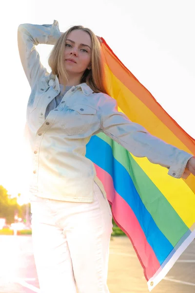 Young blonde millennial woman with LGBTQ flag outdoor. Rainbow LGBT flag. Peace and freedom the symbol of LGBT, spending and sharing loving time. Support LGBTQ community — Stock Photo, Image