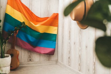 Arka planda ve şapkada LGBTQ bayrağı olan hippi tarzı bir balkon. Merkez ofis. Evde kal.