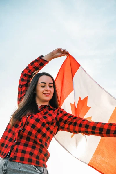 年轻的千年黑发女子举着加拿大国旗。加拿大国旗或枫叶。游客或爱国心。移民到一个自由的国家。独立日7月1日 — 图库照片