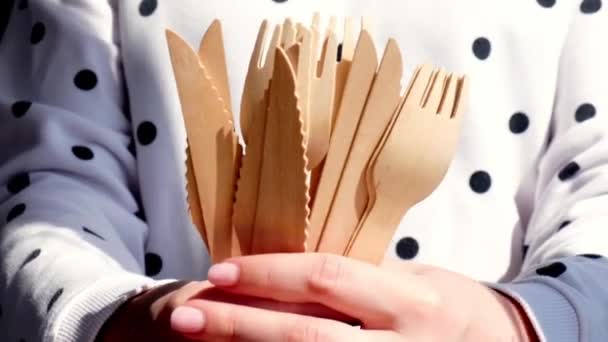 Manos femeninas de cámara lenta sosteniendo tenedores de madera y vasos de papel con platos. Vajilla desechable ecológica. Utilizado en comida rápida, restaurantes, comida para llevar, picnics. Sin plástico — Vídeos de Stock