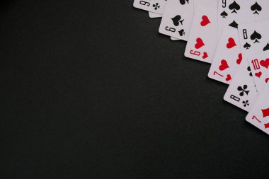 Fotokopi alanı olan siyah arkaplanda kart oynuyorum. Aileniz ve arkadaşlarınız için evde kalıp boş vakit geçirin. İskambil kağıdıyla çerçevele. Poker kartları. Poster