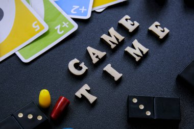 Kiev Ukrayna - 10.03.21 Metin Oyun Süresi Tahta harfle yazılıyor. Zarlarla çevrili dominolar siyah arka planda kağıt oynuyorlar. Masa oyunları. Çocukların aileleri için evde kalmak.