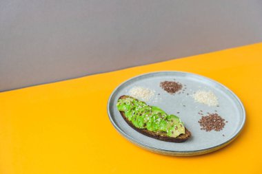 Sağlıklı avokado tostu için gerekli malzemeler. Susamlı keten tohumu. Vejetaryen keto diyeti. Sağlıklı beslenme. Vejetaryen modası geçmiş guacamole. Moda renklerinde izometrik tarzda minimal kavram.
