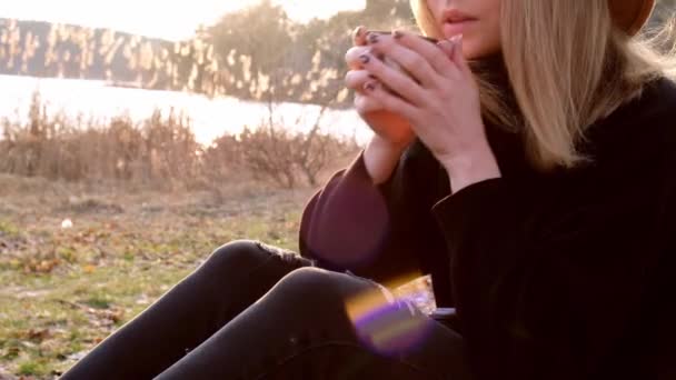 Tysiącletnia kobieta 4k kaukaska blondynka w beżowym kapeluszu w czarnym swetrze pije gorącą herbatę z termosu na wsi. Złota godzina, domek letniskowy. Podróże lokalne. Wolne życie. Zdrowie psychiczne — Wideo stockowe