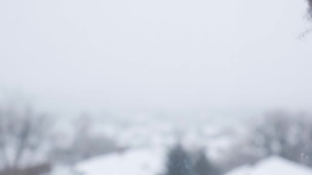 Snö faller. Snötäckt stad och flygande snöflingor i slow motion. Oskärpa. Selektivt fokus. suddig vinter bakgrund kallt väder — Stockvideo