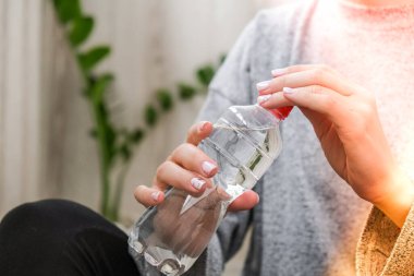 Bin yıllık sarışın kadın bir şişe su içiyor ve balkonda yoga egzersizi yapıyor. Bilinçli meditasyon. Rahatla. Rahat nefes al. Spor salonu pozu ver..