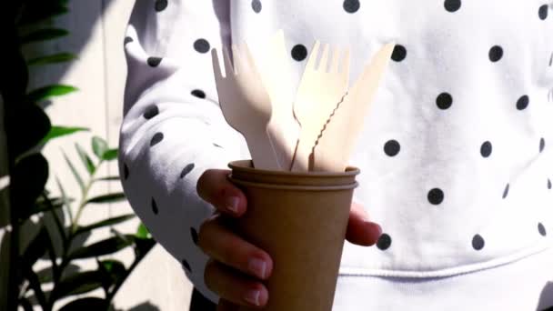 Movimento lento Mãos femininas segurando garfos de madeira e copos de papel com placas. Eco amigável utensílios de mesa descartáveis. Usado em fast food, restaurantes, takeaways, piqueniques. Sem plástico — Vídeo de Stock