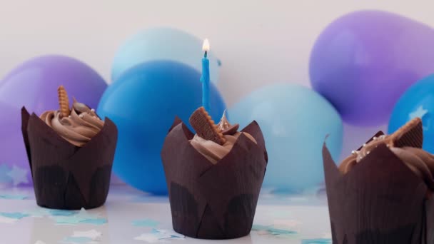 Heerlijke chocolade cupcakes met room en kaarsen branden. Vlam Drie chocolade muffin. Verjaardagstaart feestje. Jongen of meisje baby feesttaart. Babydouche — Stockvideo
