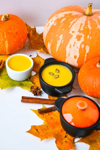 Autumn food. Pumpkin puree soup, leaves. Autumn harvest, pumpkins, leaves on grey as abstract background. Thanksgiving day.