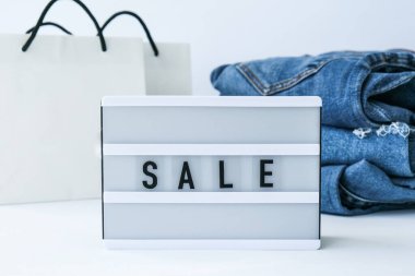 Kağıt alışveriş torbaları, kot giysileri olan kısa pano satışı. İnternetten alışveriş konsepti. Promosyon reklamcılığı. Tatil Siber Pazartesi.