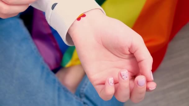 4k Closeup de jovem caucasiano millennial hippie mulher mostrando bandeira do arco-íris em forma de coração pintado no pulso. Tatuagem de cor arco-íris, símbolo do mês de orgulho LGBT — Vídeo de Stock