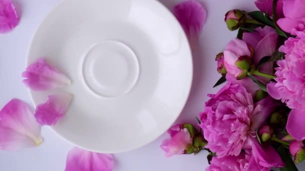 4k Mise en page créative avec des pivoines roses fleurs. Main féminine tenant une tasse de thé sur une table lumineuse. Printemps Saint-Valentin saisonnier, femme, mère, 8 Mars vacances, petit déjeuner romantique. Blogueur élégant. — Video