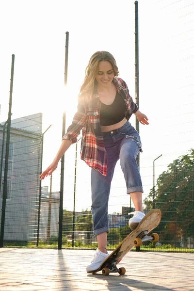 路上でスケートボードに乗っている女性。長いボードの上のスケーターの女の子。日没時にクールな女性スケートボーダー。フリースケーター20代女性の自由なライフスタイルを楽しむホビー — ストック写真