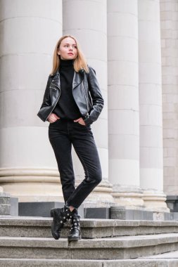Şirket binasının merdivenlerinde kırmızı dudaklı, deri ceketli genç sarışın kadın portresi. Kariyer sahibi bir iş kadını. Kentsel sokak hayatı