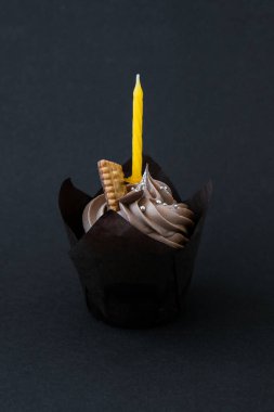 Koyu arkaplanda mum ve kremalı lezzetli çikolatalı kek. Çikolatalı kek. Doğum günü pastası partisi. Ev yapımı fırın.