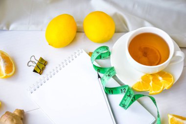 Limon, zencefil, papatya çayı, beyaz arka planda şerit. Kopya alanı ve kalemi olan boş bir defter. Sağlıklı yaşam konsepti. Tarif.
