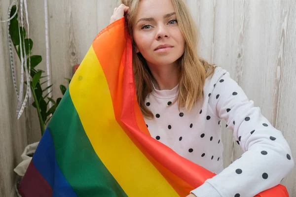 家のバルコニーで虹のLgbtqの旗を持つ若いブロンドの千年ヒッピー女性 平和と自由はLgbtの象徴であり 愛情のある時間を費やして分かち合います Lgbtqコミュニティを支援する 若いですレズビアン女性 — ストック写真