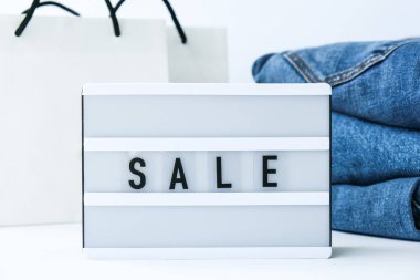Kağıt alışveriş torbaları, kot giysileri olan kısa pano satışı. İnternetten alışveriş konsepti. Promosyon reklamcılığı. Tatil Siber Pazartesi.