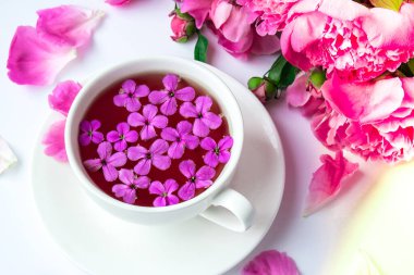 Pembe şakayık çiçekleri ve parlak masa üzerinde bir fincan çayla yaratıcı bir düzen. Bahar mevsimi sevgililer günü, kadın, anne, 8 Mart bayramı, romantik kahvaltı. Şık bir blog yazarı. Tebrik kartı. Davetiye. Günlük postası