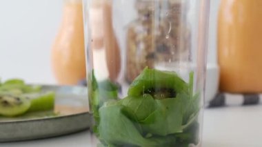 Sağlıklı smoothie pişiren 4k kadın yeşil elma, blender yeşil smoothie ile harmanlanmış kivi ıspanağı. Diyet, zayıflama, kilo kaybı ve yemek planlama konsepti.