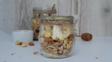 4K sağlıklı kahvaltı. Yunan yoğurdu dökülmüş yulaf ezmesi ve hafif arka planda muzlu müsli. Vejetaryen, vejetaryen ve kilo verme diyeti. Detox menüsü.
