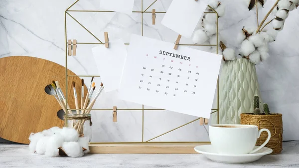 SEPTEMBER CALENDAR cards and posters mock ups on grid board. Copy space. Home office desktop. Freelance bloggers workplace. Brushes and palette