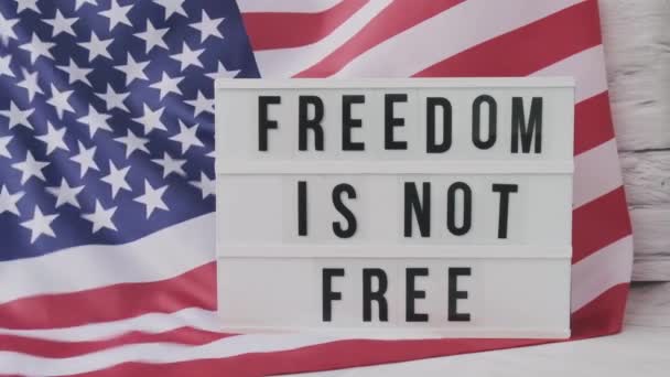 Slow motion zwaaiende Amerikaanse vlag achtergrond. Lightbox met tekst FREEDOM IS NIET GRATIS Vlag van de Verenigde Staten van Amerika. 4 juli Onafhankelijkheidsdag. USA patriottisme nationale feestdag. Usa trots. — Stockvideo