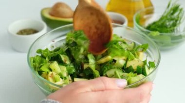 Kadın taze yeşil sebze salatasıyla otları karıştırıyor. Çiğ gıda konsepti. Vejetaryen menüsü. Sağlıklı beslenme ya da vejetaryen yemekleri pişirmek. Adım adım tarif.