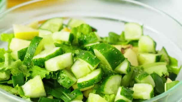 Donna che cucina insalata di verdure verdi fresche ed erbe. Concetto di cibo crudo. Menù vegano. Cucina dieta sana o cibo vegetariano. Mani femminili tagliano il cetriolo sul tagliere circondato da verde — Video Stock