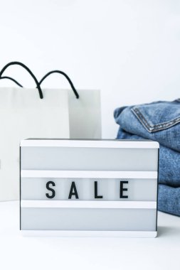 Kağıt alışveriş torbaları, kot giysileri olan kısa pano satışı. İnternetten alışveriş konsepti. Promosyon reklamcılığı. Tatil Siber Pazartesi.