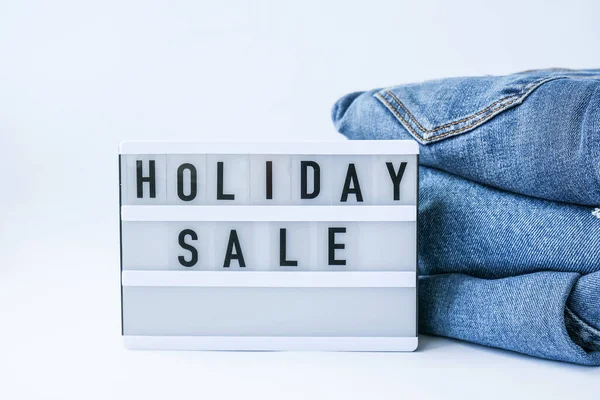 Light board with text HOLIDAY SALE with paper shopping bags, jeans clothes. Big Sale online shopping concept. Promotion advertising. Holiday Cyber monday.