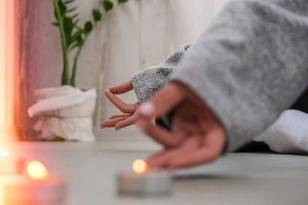 Primer plano. Mujer haciendo ejercicio de yoga en casa. Meditación de atención plena. Relajarse respirar fácil pose gimnasio estilo de vida saludable concepto. Velas encendidas. Lotus asana. Ambiente de relax y zen. — Foto de Stock