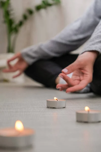 Close-up. Woman doing yoga exercise at home. Mindfulness meditation. Relax breathe easy pose gym healthy lifestyle concept. Burning candles light. Lotus asana. Atmosphere of relax and zen.