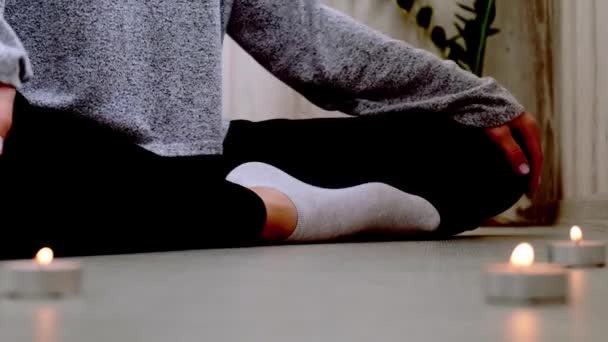 Een close-up. Een vrouw die thuis yoga doet. Mindfulness meditatie. Relax adem gemakkelijk poseren fitnessruimte gezonde levensstijl concept. Kaarsen branden. Lotus asana. Sfeer van ontspanning en zen. — Stockvideo