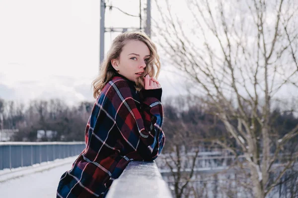 Curly blond pretty young woman in poncho in winter park. Cold weather. Holidays, season and leisure concept. Christmas, New year. — Stock Photo, Image