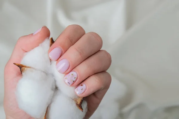 Woman hands with beautiful nude modern design manicure holding delicate white cotton flower. Female Manicure, natural look. Nails care. Self care. — Stock Photo, Image