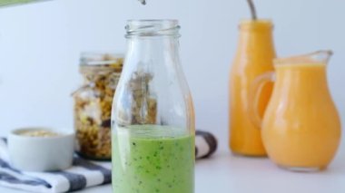 Ağır çekimde, Matcha yeşili vejetaryen smoothie hazırlayan kadın çim tohumları ve naneli içecek detoks kahvaltısı ile cam şişe dolduruyor. Temiz yemek, kilo kaybı, sağlıklı beslenme konsepti.