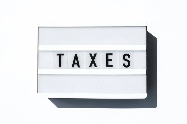 Tablica Lightbox Białym Tle Słowami Taxes Czarnymi Literami Waluta Gotówka — Zdjęcie stockowe