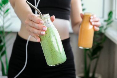 Yeni nesil sarışın kadın vejetaryen smoothie içiyor. Evde yoga egzersizi yapan bir kadın. Temiz yemek, kilo kaybı, sağlıklı beslenme konsepti. Sağlıklı kalın. Zindelik