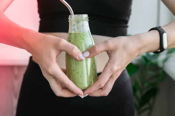 Kalp sembolü olarak, Smoothie içecek detoksunu zinde ve ince göbekli kadına tutuyordu. Fitness refah konsepti. Vücut bakımı, temiz yemek, kilo verme diyeti. Bağırsak veya üreme sorunu olan bir kadın. Evde antrenman yapıyorum. Göbek egzersizleri.
