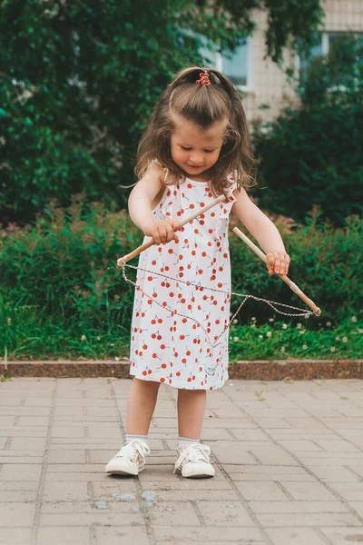 Een vrolijk meisje vangt zeepbellen met haar handen en lacht. Gelukkige jeugd, zomertijd. Portret van een jong peutermeisje — Stockfoto