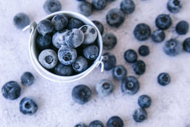Donmuş yaban mersinleri beton arka planda küçük bir kovada. Sağlıklı organik mevsimlik meyve arka planı. Organik yiyecekler. Hasat, kış için yemek hazırlamak. Süper yemek. Güzel görüş. Gözlerini açık tut.