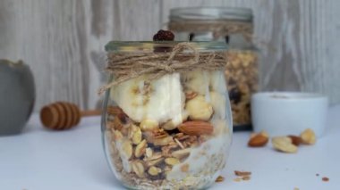 4K sağlıklı kahvaltı. Kadın el yulaf ezmesini Yunan yoğurdu ve fındıklı müsli ile hafif arka planda pişirmeye hazırlanıyor. Vejetaryen, vejetaryen ve kilo verme diyeti. Detox menüsü.