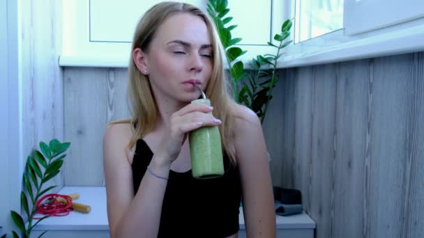 4К Молодая блондинка тысячелетия пьет веганский коктейль детоксикации. Женщина занимается йогой дома. Чистое питание, потеря веса, здоровое питание концепции. Будьте здоровы — стоковое видео