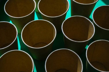 Yeşil zemin üzerinde boş geri dönüşümlü kağıt bardaklar. İçmek için bir sürü yemek fincanı. Çevre dostu. Plastiksiz sıfır konsept. Piknikler için tablo takımı