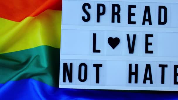 Işık kutulu 4k Gökkuşağı bayrağı ve "Nefret Etmeyen Sevgi Yayılsın" mesajı. İpek kumaştan yapılmış gökkuşağı lgbtq bayrağı. LGBTQ gurur ayının sembolü. Eşit haklar. Barış ve özgürlük — Stok video