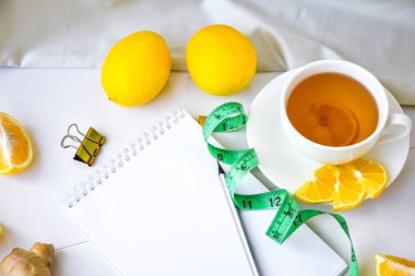 Limon, zencefil, papatya çayı, beyaz arka planda şerit. Kopya alanı ve kalemi olan boş bir defter. Sağlıklı yaşam konsepti. Tarif.