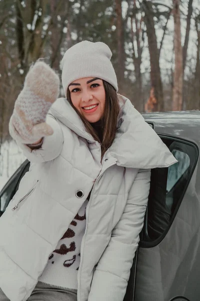 Attractive beautiful young woman in sweater staying next to the car in forest. Winter vacation. Holidays. Smilling — Stock Photo, Image